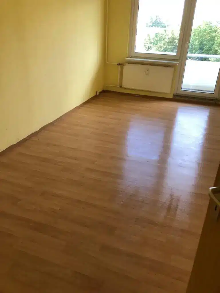 Leeres, besenreines Zimmer mit Fenster und Laminatboden